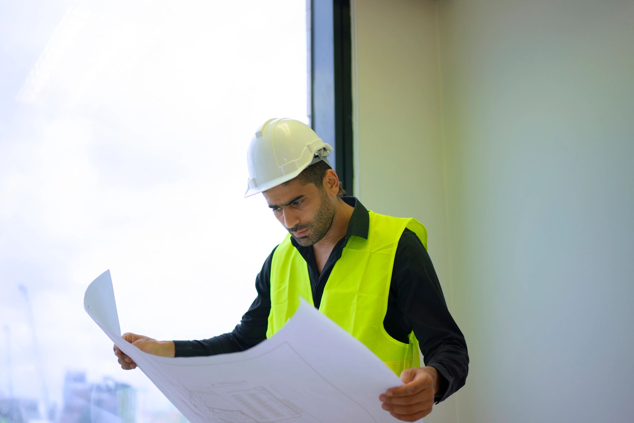 Construction professional reviewing plans on a high-rise building site